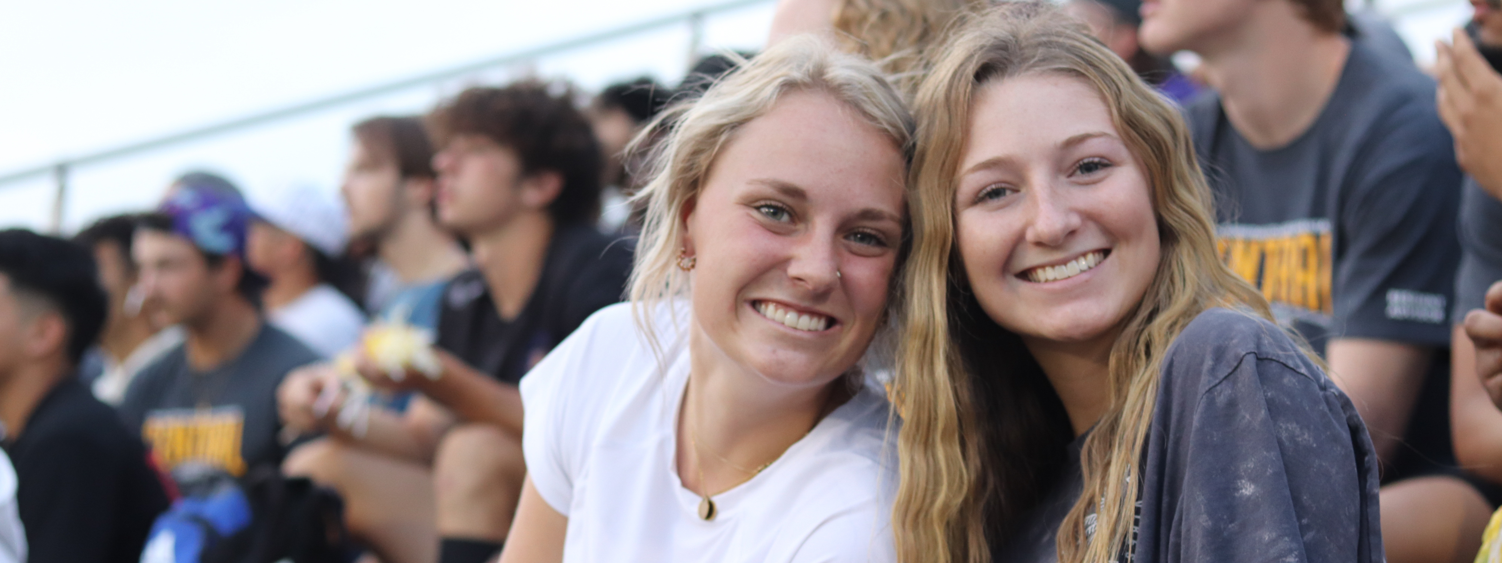 Humanities Photo Header: Central girls smiling together on the bleachers at a soccer game