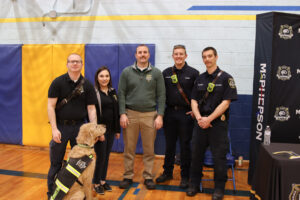 McPherson Fire Department poses for camera with service dog at feet.