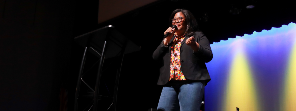 Black female speaking on the stage in Greer Auditorium
